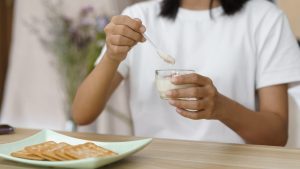 Personne prenant une gélule de probiotiques avec un verre d’eau au petit-déjeuner.